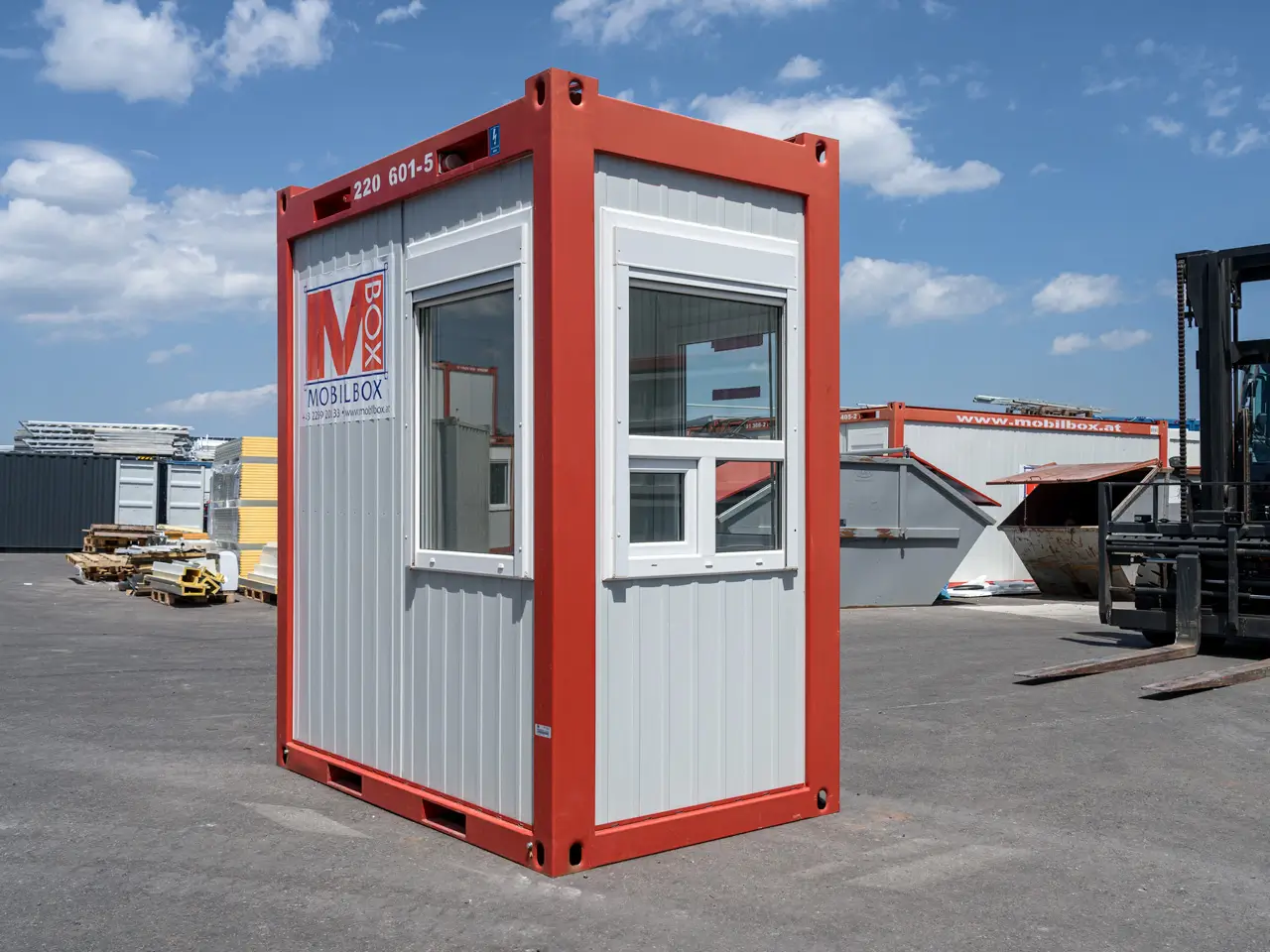 Kleiner Container genutzt als Portiercontainer mit rotem Rahmen und grauen Paneelen.