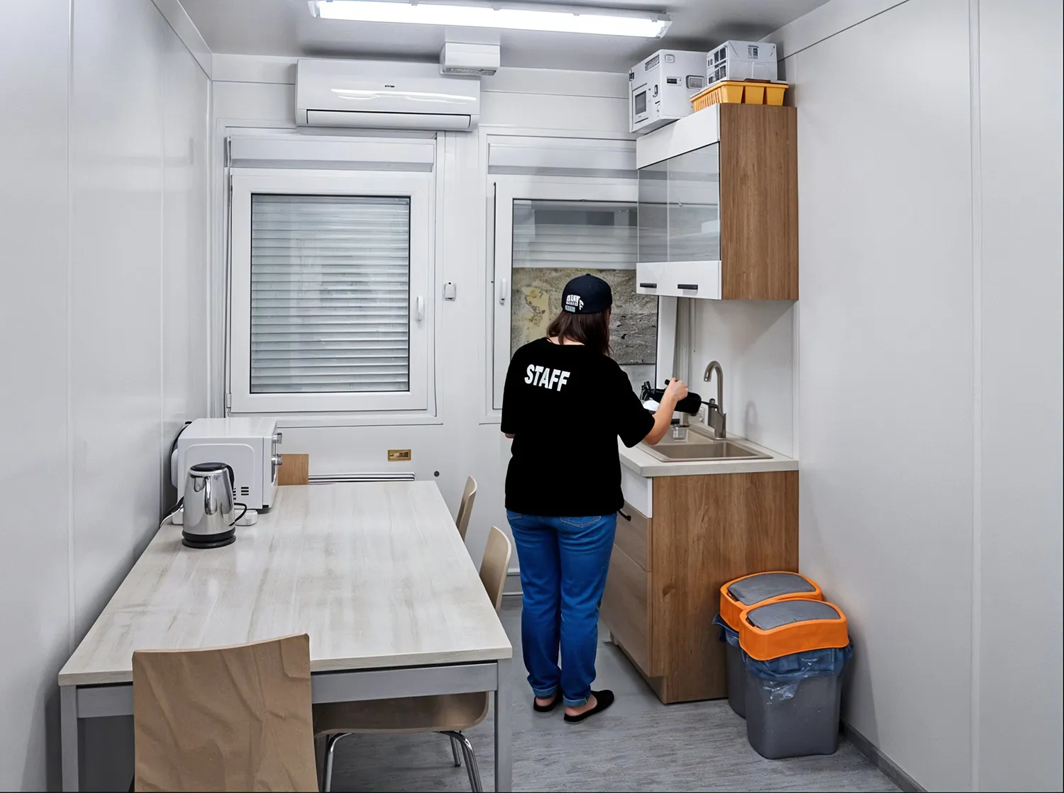 Staff Mitarbeiterin bei einem Festival wie diese einen Kaffe in einem gemieteten Wohncontainer welcher als Pausenraum genutzt wird, zubereitet.