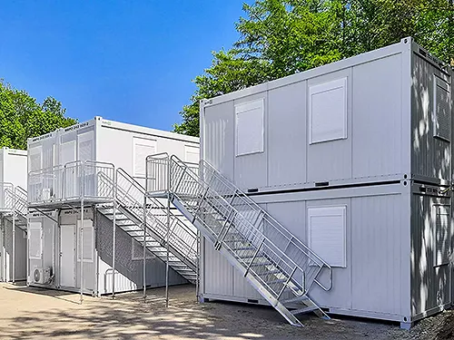 Außenfoto einer Mannschaftscontainer-Anlage gekauft von dem Kunden in RAL 7035 mit Außentreppen aus verzinktem Stahl.